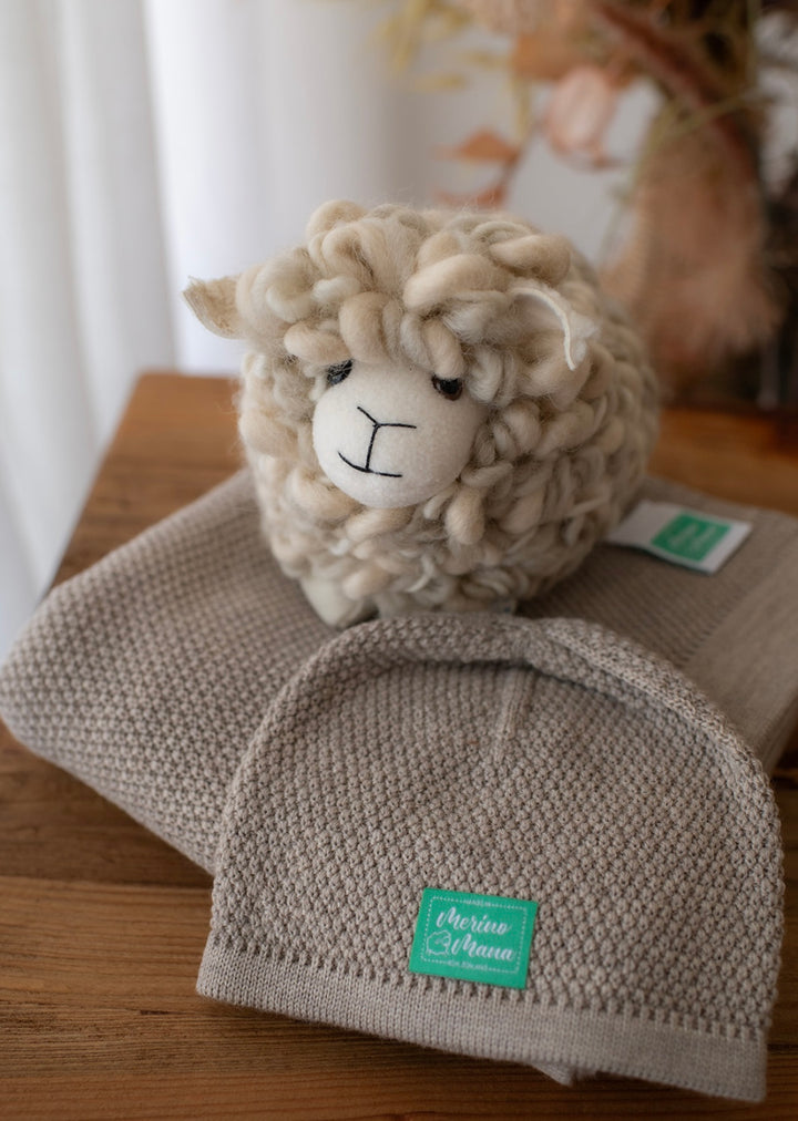 A merino wool baby blanket and beanie gift set with a textured moss stitch pattern with a toy sheep. All items made in New Zealand. 